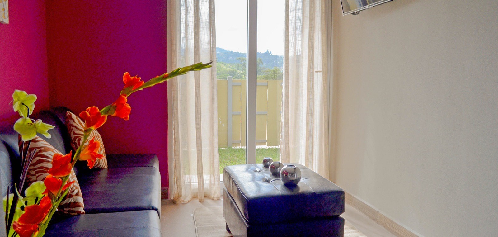 Sala de un apartamento de Distrito Verde con ventanal al jardín